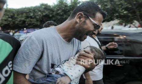 Seorang pria membawa seorang anak yang terluka di sebuah rumah sakit di Khan Younis menyusul pengeboman Israel, Jalur Gaza selatan, 26 Oktober 2023.