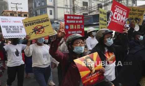 Para pengunjuk rasa memegang spanduk dan isyarat dengan tanda tiga jari perlawanan saat mereka memprotes kudeta militer di Mandalay, Myanmar, Jumat, 12 Maret 2021. Pasukan keamanan Myanmar menembak mati sedikitnya 10 orang yang memprotes kudeta militer menolak PBB Dewan Keamanan mengajukan banding untuk berhenti menggunakan kekuatan mematikan.