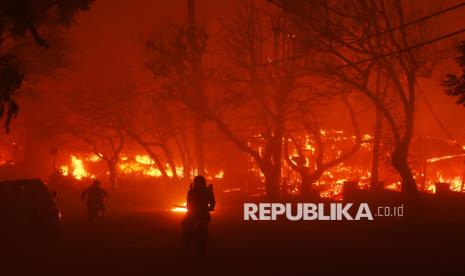 Dua orang warga melintas saat terjadinya kebakaran besar yang melanda kawasan Pacific Palisades, Los Angeles, California, Selasa (7/1/2025) waktu setempat. Kebakaran hutan yang dipicu oleh angin kencang melanda lereng bukit Los Angeles, menghanguskan sedikitnya 770 hektare lahan termasuk permukiman warga. Kebakaran terus meluas akibat hembusan angin kencang. Evakuasi sedang dilakukan karena potensi ancaman terhadap nyawa dan harta benda. Sebanyak 30.000 orang dievakuasi akibat kebakaran tersebut yang saat ini terus meluas.