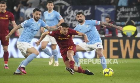 Pemain Roma Paulo Dybala (tengah) berebut bola dengan pemain Lazio Elseid Hysaj (kanan) pada pertandingan sepak bola Serie A Italia antara Lazio dan Roma di stadion Olimpiade Roma, Senin (20/3/2023) dini hari WIB. 