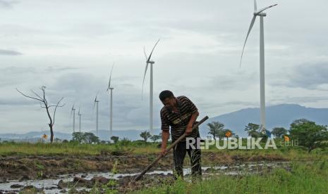 Petani menggarap sawahnya di sekitar lokasi Pembangkit Listrik Tenaga Bayu (PLTB) Tolo, Kabupaten Jeneponto, Sulawesi Selatan, Minggu (27/11/2022). Kementerian Energi Sumber Daya Mineral (ESDM) menargetkan kapasitas pembangkit energi bersih pada tahun 2060 mencapai 587 gigawatt dan 39 gigawatt diantaranya atau 6,64 persen bersumber dari PLTB guna mewujudkan netralitas karbon di dalam negeri. 