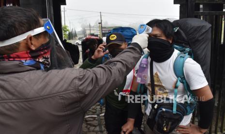 Petugas memeriksa suhu tubuh calon pendaki di pintu gerbang jalur pendakian Gunung Lawu di Cemoro Sewu, Magetan, Jawa Timur. Pemerintah Kabupaten Magetan, Jawa Timur, menyatakan jumlah warga setempat yang terinfeksi poistif COVID-19 bertambah sembilan orang, sehingga total kasus COVID-19 di wilayah setempat menjadi 619 orang, naik dari sebelumnya 610 orang.