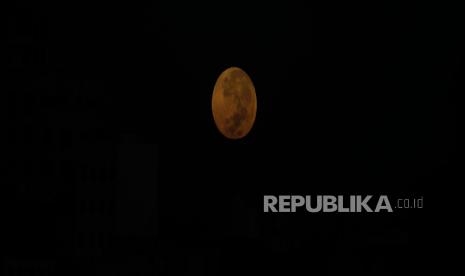 Bulan purnama terbenam di atas lingkungan di Sana