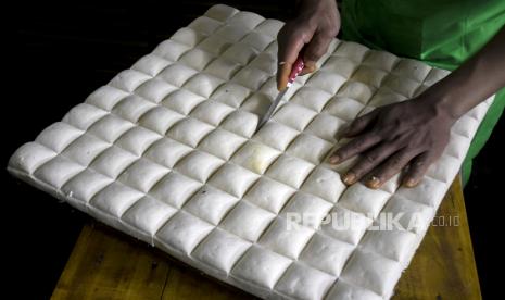 Pekerja memotong tahu di Pabrik Tahu NJ, Jalan Terusan Pasirkoja, Babakan Ciparay, Kota Bandung, Rabu (16/2/2022). Sejumlah perajin tahu tempe di Bandung berencana akan melakukan mogok produksi pada 21-23 Februari 2022, akibat tingginya harga kedelai yang mencapai Rp11.500 yang sebelumnya hanya Rp9 ribu. Meski demikian, Pemerintah Kota Bandung melalui Dinas Perdagangan dan Industri (Disdagin) Kota Bandung meminta perajin untuk tidak mogok produksi dan mempersilakan para perajin untuk menaikkan harga. Foto: Republika/Abdan Syakura