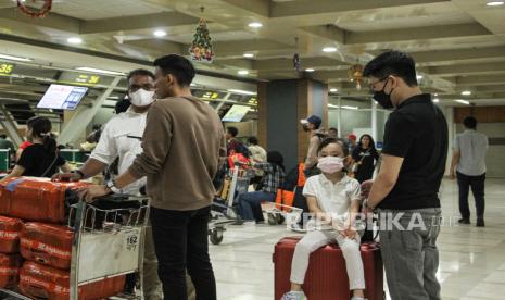 Seorang bocah memakai masker saat mengantre bersama keluarganya di terminal keberangkatan Bandara Internasional Sultan Hasanuddin, Maros, Sulawesi Selatan, Jumat (22/12/2023). Pengelola bandar udara setempat mengeluarkan imbauan penggunaan masker di kawasan bandara maupun di pesawat khususnya bagi penumpang dan petugas yang mengalami gangguan kesehatan sebagai upaya mengantisipasi penyebaran COVID-19. 