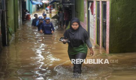 Warga melintasi banjir yang melanda permukiman warga di Kebon Pala, Kelurahan Kampung Melayu, Jatinegara, Jakarta Timur, Kamis (28/11/2024). Puncak musim hujan diprediksi terjadi Januari 2025.