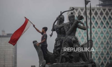 Massa yang tergabung dari masyarakat sipil dan mahasiswa mengibarkan bendera merah putih di atas Patung Kuda saat aksi di Jakarta, Selasa (20/10). Massa menuntut penolakan terhadap Omnibus Law Undang-Undang Cipta Kerja sekaligus peringatan satu tahun pemerintahan Joko Widodo-Maruf Amin. Republika/Thoudy Badai