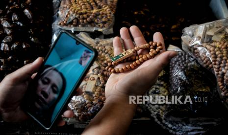 Seseorang memegang tasbih yang merupakan salah satu atribut umat Islam. Apa hukumnya ketika orang Islam memakai atribut dari agama lain?