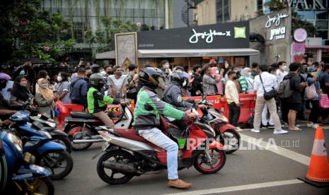 Pengendara menunggu pergaan busana sebelum melintas di area zebra cross yang dijadikan lokasi peragaan busana Citayam Fashion Week di kawasan Dukuh Atas, Jakarta, Rabu (27/7/2022). Sejumlah petugas gabungan dari Dishub dan Satpol PP melakukan penjagaan dan normalisasi fungsi zebra cross untuk penyeberangan serta perlintasan kendaraan motor dan mobil. Meski demikian, kegiatan fashion show jalanan tersebut masih tetap berlangsung dengan imbauan untuk menjaga ketertiban agar tidak terjadi kemacetan. Republika/Thoudy Badai