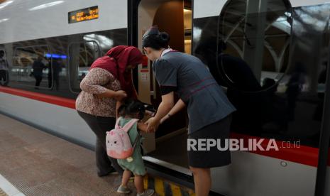 Penumpang dibantu pramugari kereta saat menaiki kereta cepat WHOOSH Stasiun Halim, Jakarta, Selasa (17/10/2023). 