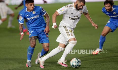 Usaha striker Real Madrid Karim Benzema (tengah) dalam menjebol pertahanan Getafe pada lanjutan La Liga Spanyol 2019/2020, Jumat (3/7).