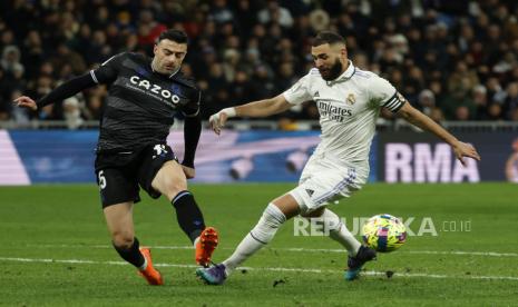 Striker Real Madrid Karim Benzema (kanan) berduel memperebutkan bola dengan bek Real Sociedad Diego Rico (kiri) dalam pertandingan sepak bola LaLiga Spanyol antara Real Madrid dan Real Sociedad, di Madrid, Spanyol, 29 Januari 2023.