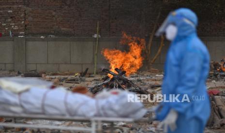 Salah satu kerabat menunggu untuk melakukan upacara terakhir untuk korban COVID-19 di tempat kremasi di New Delhi, India,  Kamis (29/4).