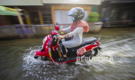 Pengendara motor melintasi banjir akibat luapan Sungai Martapura di Kelayan A, Banjarmasin, Kalimantan Selatan, Senin (5/4/2021). Banjarmasin Waspada Cuaca Ekstrem Hujan dan Angin Kencang