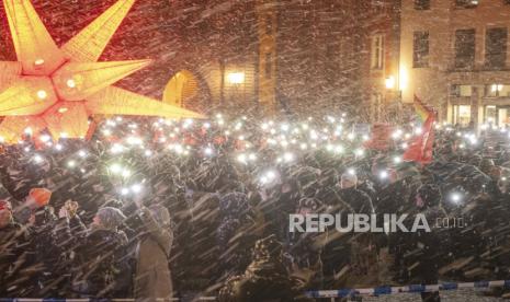 Orang-orang berdiri di tengah salju di Alter Markt saat mereka memprotes AfD dan ekstremisme sayap kanan di Stralsund, Jerman, Jumat (19/1/2024).