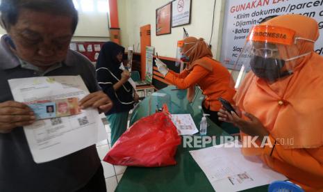 Petugas memotret warga penerima bantuan sebaga tanda bukti pencairan Bantuan Sosial Tunai (BST) di Kantor Pos 