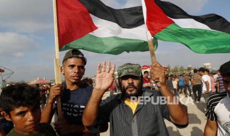  Para pengunjuk rasa mengibarkan bendera nasional mereka di dekat pagar perbatasan Jalur Gaza dengan Israel, selama protes menandai peringatan serangan pembakaran 1969 di masjid Al-Aqsa Yerusalem oleh seorang turis Australia yang kemudian ditemukan sakit jiwa, di sebelah timur Kota Gaza, Sabtu, 21 Agustus 2021.