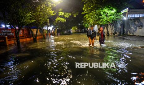 Dua orang warga melintasi jalan yang tergenang banjir di Rancabolang, Bandung, Jawa Barat akibat hujan terus menerus (Ilustrasi)