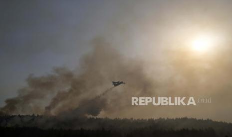  Sebuah pesawat menjatuhkan air di atas api di daerah Varibobi, Athena utara, Yunani, Rabu, 4 Agustus 2021. Pesawat pemadam kebakaran melanjutkan operasi pada Rabu cahaya pertama untuk mengatasi kebakaran hutan besar di pinggiran utara Athena yang melaju ke daerah pemukiman hari sebelumnya, memaksa ribuan orang meninggalkan rumah mereka di tengah gelombang panas terburuk Yunani dalam beberapa dekade.