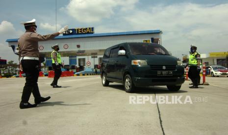 Petugas kepolisian menghentikan kendaraan saat penyekatan di pintu keluar tol Adiwerna, Kabupaten Tegal, Jawa Tengah, Sabtu (25/4/2020). Penyekatan oleh Polres Tegal, PMI dan Dinas Perhubungan Kabupaten Tegal itu dilakukan menyusul adanya larangan mudik oleh Pemerintah guna mencegah penyebaran COVID-19