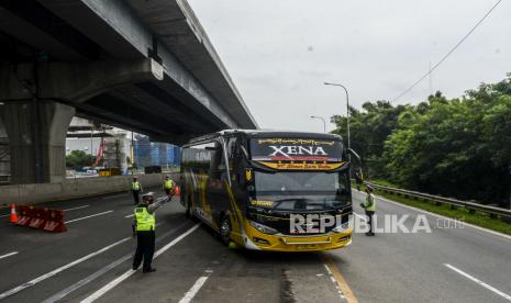 Sejumlah polisi menghentikan bus yang membawa penumpang saat penerapan pelarangan mudik di tol Jakarta-Cikampek, Cikarang, Kabupaten Bekasi, Jawa Barat, Sabtu, (25/4). Hari kedua penerapan pelarangan mudik di akses tol Jakarta - Cikampek masih banyak pengendara yang memaksakan untuk mudik dan tidak menerapkan jarak sosial