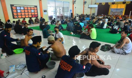 Relawan dari Pondok Pesantren An-Najach menghapus tato peserta saat layanan hapus tato gratis di Desa Jurang, Gebog, Kudus, Jawa Tengah, Senin (29/3/2022). Aksi kepedulian sosial membersihkan tubuh dari tato itu diikuti sebanyak 100 peserta. 