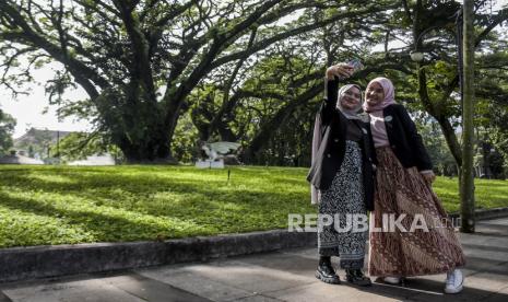 Peserta mengenakan batik berfoto disela kegiatan Batik Walk di Taman Balai Kota Bandung, Jalan Wastukencana, Kota Bandung, Ahad (9/10/2022). Kepatuhan penuh terhadap aturan ruang terbuka hijau 3-30-300 erat kaitannya dengan kesehatan masyarakat mental yang lebih baik. 