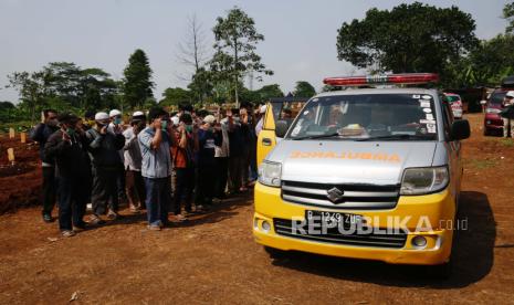 Kerabat berdoa di depan ambulans yang membawa peti mati orang tua yang meninggal karena komplikasi penyakit COVID-19 di pemakaman di Depok, Indonesia, 09 Agustus 2021. 