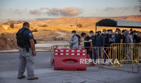 Dalam file foto 30 Juni 2020 ini, para pekerja Palestina berbaris untuk melintasi sebuah pos pemeriksaan di pintu masuk pemukiman Israel di Maale Adumim, dekat Yerusalem. Pada hari Minggu, 28 Februari 2021, Israel mengumumkan rencana untuk memvaksinasi puluhan ribu warga Palestina yang bekerja di dalam Israel dan permukiman Tepi Baratnya, pada saat terdapat perbedaan besar dalam akses ke vaksin antara penduduk Israel dan Palestina.