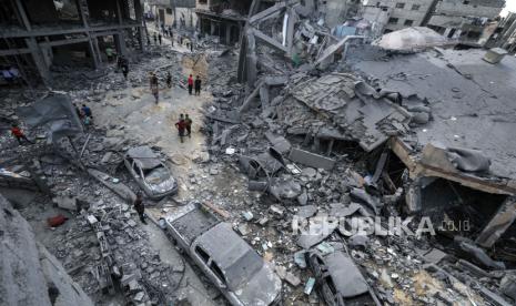 Warga Palestina terlihat berjalan di tengah wilayah yang hancur usai serangan udara Israel di Kota Gaza pada 9 Oktober 2023.