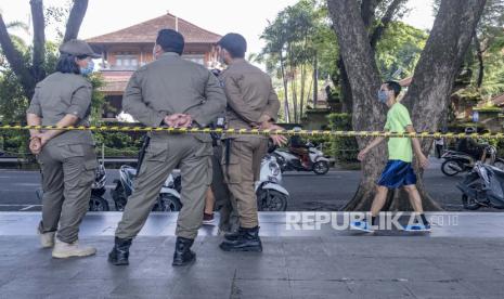 Bali Gunakan 17 Hotel untuk Karantina Pasien Covid-19. Petugas polisi kota berdiri selama kampanye pemakaian masker dan protokol kesehatan masyarakat di sebuah pos pemeriksaan di Denpasar, Bali, Indonesia, 28 Januari 2021. Indonesia telah melaporkan lebih dari satu juta kasus COVID-19 sejak awal pandemi, jumlah tertinggi di Asia Tenggara.