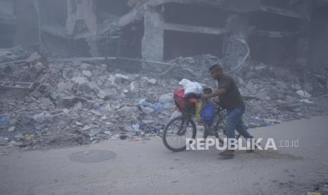 Warga Palestina berjalan melintasi puing-puing rumah yang hancur akibat serangan Israel di Khan Younis, Jalur Gaza, Senin (22/7/2024). Ribuan warga di Khan Younis melarikan diri dari serangan udara dan operasi militer Israel. Kementerian Kesehatan di Gaza yang dikuasai Hamas melaporkan serangan Israel ke Khan Younis, selatan Jalur Gaza tersebut menewaskan 70 orang dan melukai lebih dari 200 lainnya.