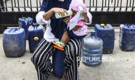 Warga memberi minum anaknya saat melakukan aksi unjuk rasa di depan Balai Kota DKI Jakarta, di Jakarta, Selasa (22/2/2022). Dalam aksinya tersebut warga Muara Angke, Jakarta Utara menuntut air minum yang layak kepada Gubernur DKI Jakarta Anies Baswedan. 