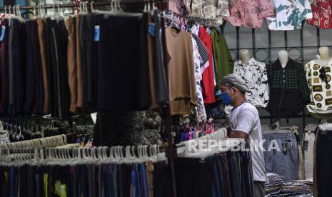 Pedagang menyusun pakaian di lapak miliknya di jalan Kramat Raya, Jakarta Utara, Minggu (17/5/2020). Meskipun dalam masa Pembatasan Sosial Berskala Besar (PSBB) tahap 2 di Jakarta, tapi pedagang tersebut tetap menggelar dagangannya di pinggir jalan