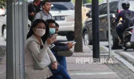 Warga  menunggu angkutan umum di halte bus, di jalan Jenderal Sudirman Jakarta, Jumat (22/6).