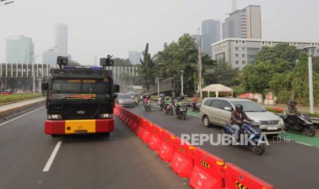 Mobil kepolisian menyemprotkan air di Jalan Jenderal Sudirman, Jakarta, Rabu (23/8/2023). Penyemprotan di sekitar jalan protokol tersebut sebagai upaya untuk membersihkan debu-debu yang bertebaran di jalanan akibat polusi udara.