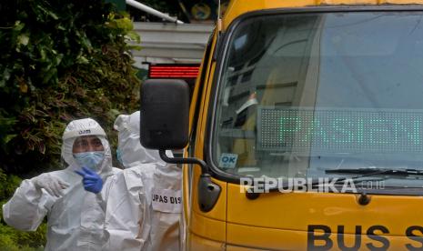 Petugas kesehatan berbincang dengan sopir bus sekolah ketika menunggu pasien Covid-19 menaiki bus di Puskesmas Kecamatan Menteng, Jakarta, Ahad (20/6). Laju kasus harian Covid-19 di Indonesia beberapa hari terakhir dalam tren menanjak, Hal ini membuat angka 2 juta kasus infeksi Covid-19 di Indonesia berada di depan mata.Prayogi/Republika. 