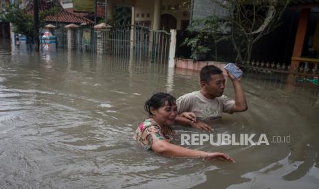 Warga melintasi genangan air yang merendam perkampunganya saat banjir di Kampung Joyotakan, Solo, Jawa Tengah, Jumat (17/2/2023). Berdasarkan data Badan Penanggulangan Bencana Daerah (BPBD) Kota Solo sebanyak 21.846 jiwa dari 15 Kelurahan di Kota Solo terdampak banjir akibat meluapnya sejumlah anak sungai Bengawan Solo. 