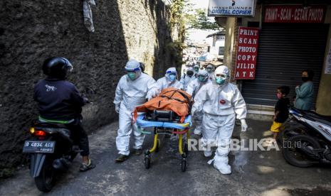 Petugas Public Safety Center 119 (PSC 119) bersama petugas puskesmas mengevakuasi jenazah pasien Covid-19 yang meninggal saat isolasi mandiri (isoman) di rumahnya di Jalan Cibarengkok, Sukajadi, Kota Bandung, Ahad (18/7). Berdasarkan hasil data yang dihimpun dari situs covid19.bandung.go.id hingga (17/7) pukul 19.09 WIB tercatat kasus terkonfirmasi Covid-19 di Kota Bandung sudah mencapai 31.175 kasus dan angka kematian akibat Covid-19 sebanyak 835 orang sementara jumlah pasien yang dinyatakan sembuh mencapai 23.734 kasus. Foto: Republika/Abdan Syakura