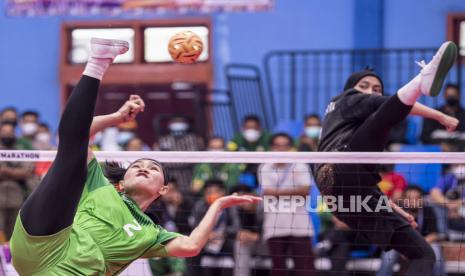 Pesepak takraw ganda putri Jawa Timur Nini Karmila (kiri) melakukan smes dengan dihadang pesepak takraw putri DKI Jakarta Asmaul Husna (kanan)  dalam final ganda putri beregu Sepak Takraw PON Papua di GOR Trikora Universitas Cenderawasih, Jayapura, Papua, Rabu (29/9/2021). Ganda putri beregu DKI Jakarta berhasil meraih medali emas usai menang atas Jawa Timur dengan skor 2-1 (21-15, 15-21, 21-14), (15-21, 21-18, 19-21), dan (21-18, 21-19). 