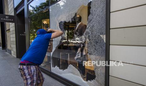 Seorang pejalan kaki mengambil foto jendela kaca showroom Canali yang hancur di pusat kota Washington, Minggu, 31 Mei 2020, setelah protes hari Sabtu berubah menjadi kekerasan, setelah kematian George Floyd, seorang pria kulit hitam Minnesota yang meninggal dalam tahanan polisi.