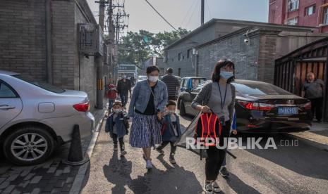 Orang tua dengan anak-anak berjalan ke taman kanak-kanak pada Hari Anak Internasional, di lingkungan Hutong, Beijing, China, 1 Juni 2021. 