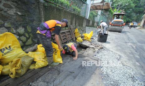 Petugas Dinas Pekerjaan Umum (DPU) berupaya membersihkan sampah dan material yang menyumbat drainase sekaligus memperbaiki jalan yang hancur saat hujan deras di Jalan Jajaway, Dago, Kota Bandung, Kamis (4/11). Banjir cileuncang saat hujan deras di kota Bandung salah satunya akibat dainase tersumbat sampah. Badan Meteorologi Klimatologi dan Geofisika (BMKG) memperingatkan akan adanya cuaca ekstrem pada Oktober - Februari 2021 yang dipicu oleh fenomena alam La Nina.