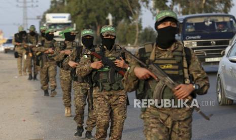 Seorang militan bertopeng dari Brigade Izzedine al-Qassam, sayap militer Hamas, mengambil posisi untuk mengamankan rekan-rekannya yang berbaris di sepanjang jalan utama kamp pengungsi Nusseirat, Jalur Gaza tengah, Kamis, 28 Oktober 2021. 