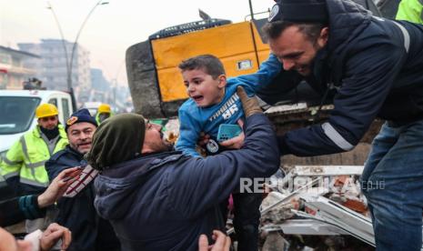 Yigit Cakmak (Tengah) yang berusia delapan tahun menangis setelah diselamatkan dari lokasi bangunan yang runtuh, sekitar 52 jam setelah gempa besar, di Hatay, Turki, Rabu (8/2/2023). Lebih dari 7.000 orang tewas dan ribuan lainnya terluka setelahnya dua gempa besar melanda Turki selatan dan Suriah utara pada Senin (6 /2/2023).