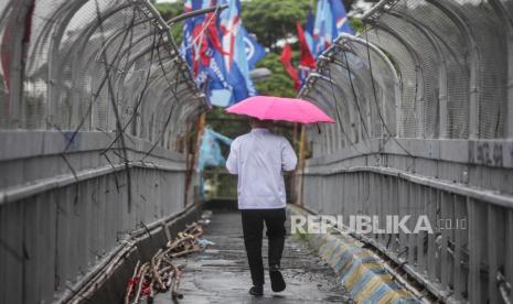 Warga memakai payung saat hujan turun di Jalan Gatot Subroto, Jakarta Selatan, Jumat (19/1/2024). Cuaca Hari Ini: Sebagian Besar Wilayah Indonesia Hujan Ringan