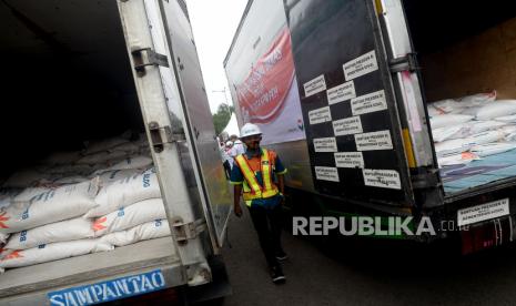 Pekerja melintas di dekat truk pengangkut beras bantuan saat peluncuran program bantuan sosial beras di Komplek Gudang BULOG, Jakarta, Rabu (2/9). Kemensos dan perum BULOG meluncurkan program bantuan sosial beras kepada 10 juta keluarga penerima manfaat program keluarga harapan (KPM-PKH) di seluruh Indonesia, termasuk keluarga petani yang terkena dampak covid-19 untuk masa waktu Agustus- Oktober 2020.Prayogi/Republika 