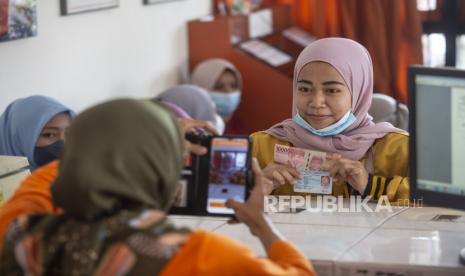 Warga penerima pantuan difoto oleh petugas saat mengambil Bantuan Subsidi Upah (BSU) di Kantor Pos Sedayu, Bantul. Direktur Utama PT Pos Indonesia (Persero) menyampaikan bahwa saat ini manajemen perusahaan sedang menyusun roadmap 2023 Pos Indonesia menuju Perusahaan BUMN Logistik. 