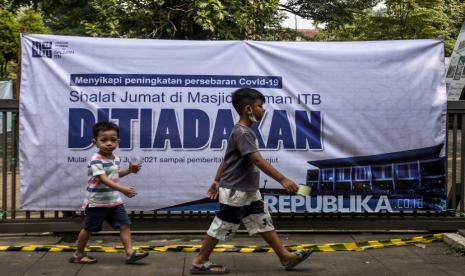 Sejumlah anak melintas di dekat spanduk pemberitahuan di depan Masjid Salman ITB, Jalan Ganesa, Kota Bandung, Jumat (25/6). Pengurus DKM Masjid Salman ITB meniadakan sementara ibadah Shalat Jumat yang berlaku mulai Jumat (25/6). Keputusan tersebut sebagai tindak lanjut dari perubahan status Kota Bandung menjadi zona merah Covid-19 dan Surat Edaran Menteri Agama Nomor 13 Tahun 2021 tentang Pembatasan Pelaksanaan Kegiatan Keagamaan di Rumah Ibadah. Foto: Republika/Abdan Syakura