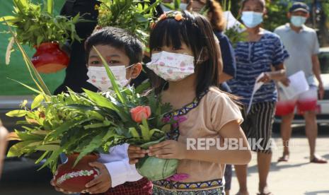 Anak-anak dan pengunjuk rasa anti-kudeta membawa pot dengan bunga dan daun untuk menandai festival Thingyan pada hari Selasa 13 April 2021 di Yangon, Myanmar.